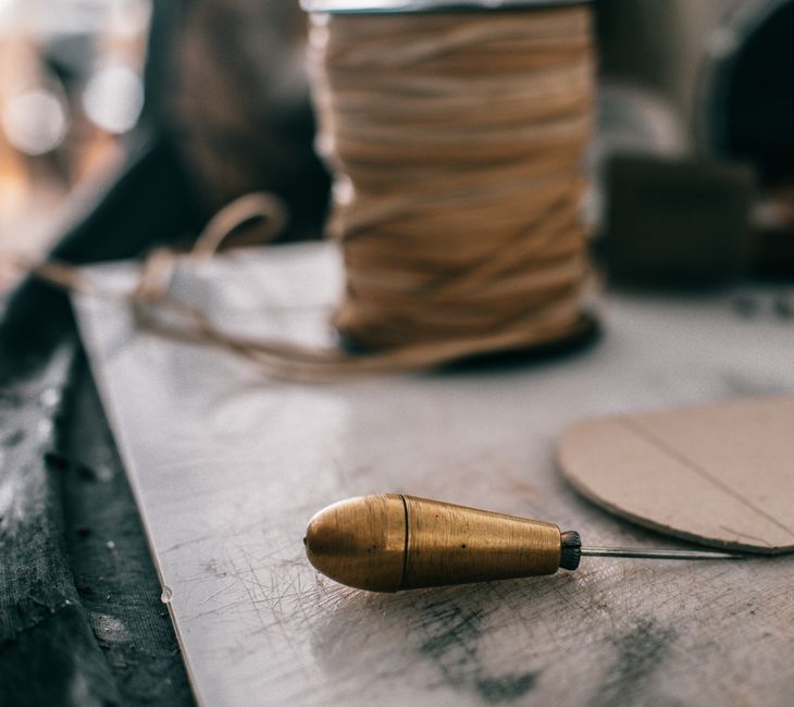 Closeup of sharp awl with metal handle lying on working bench in professional atelier studio