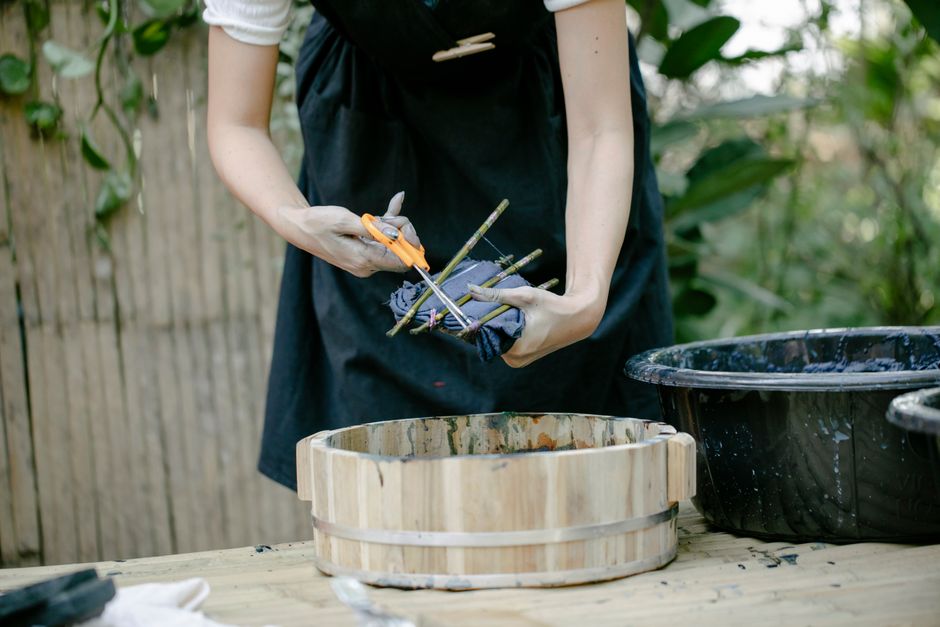 Person using natural dyes in a garden setting, showcasing hands and tools in outdoor craft activity.